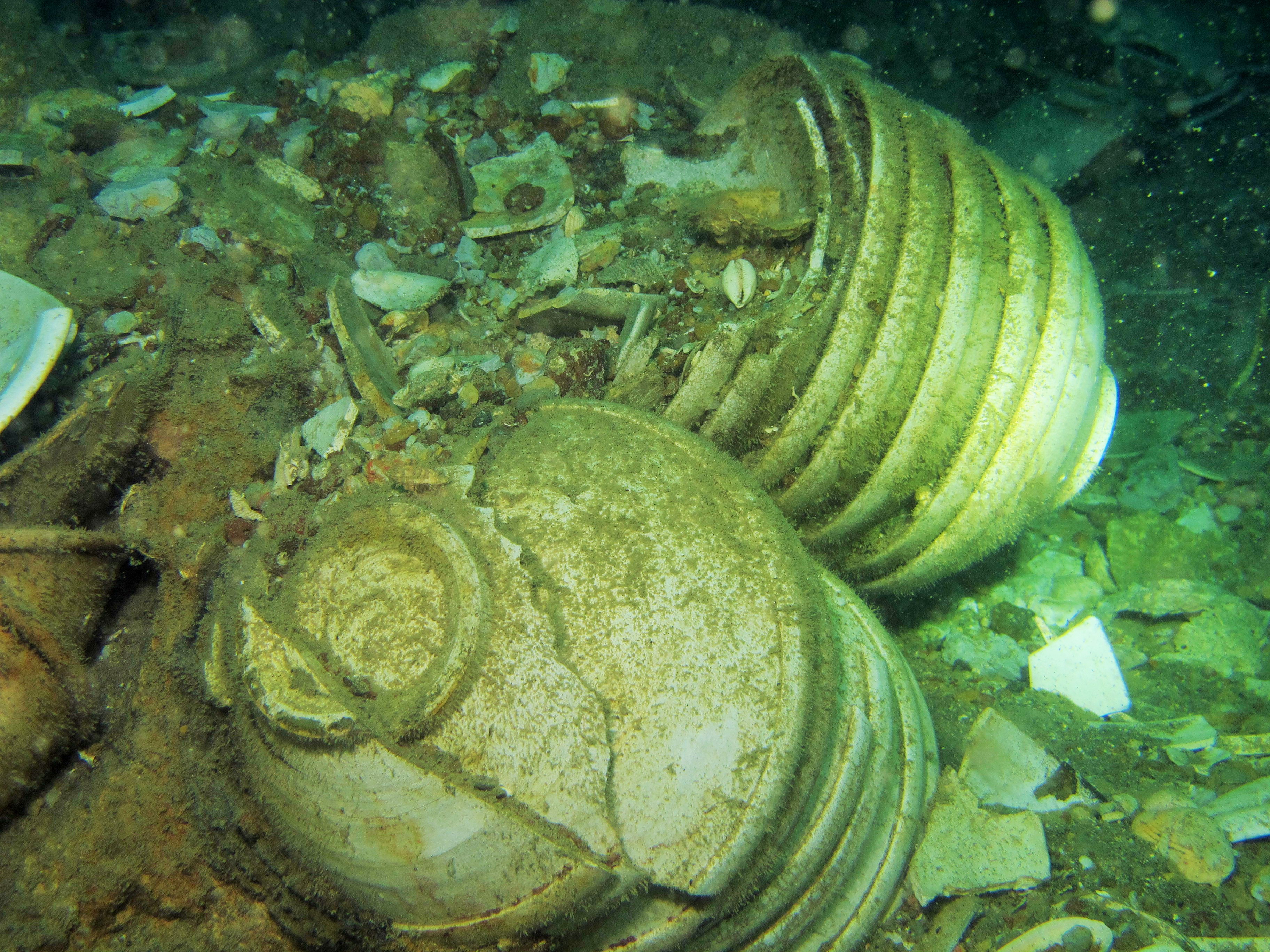 Stacks of folded-rim bowls stuck to an iron concretion.