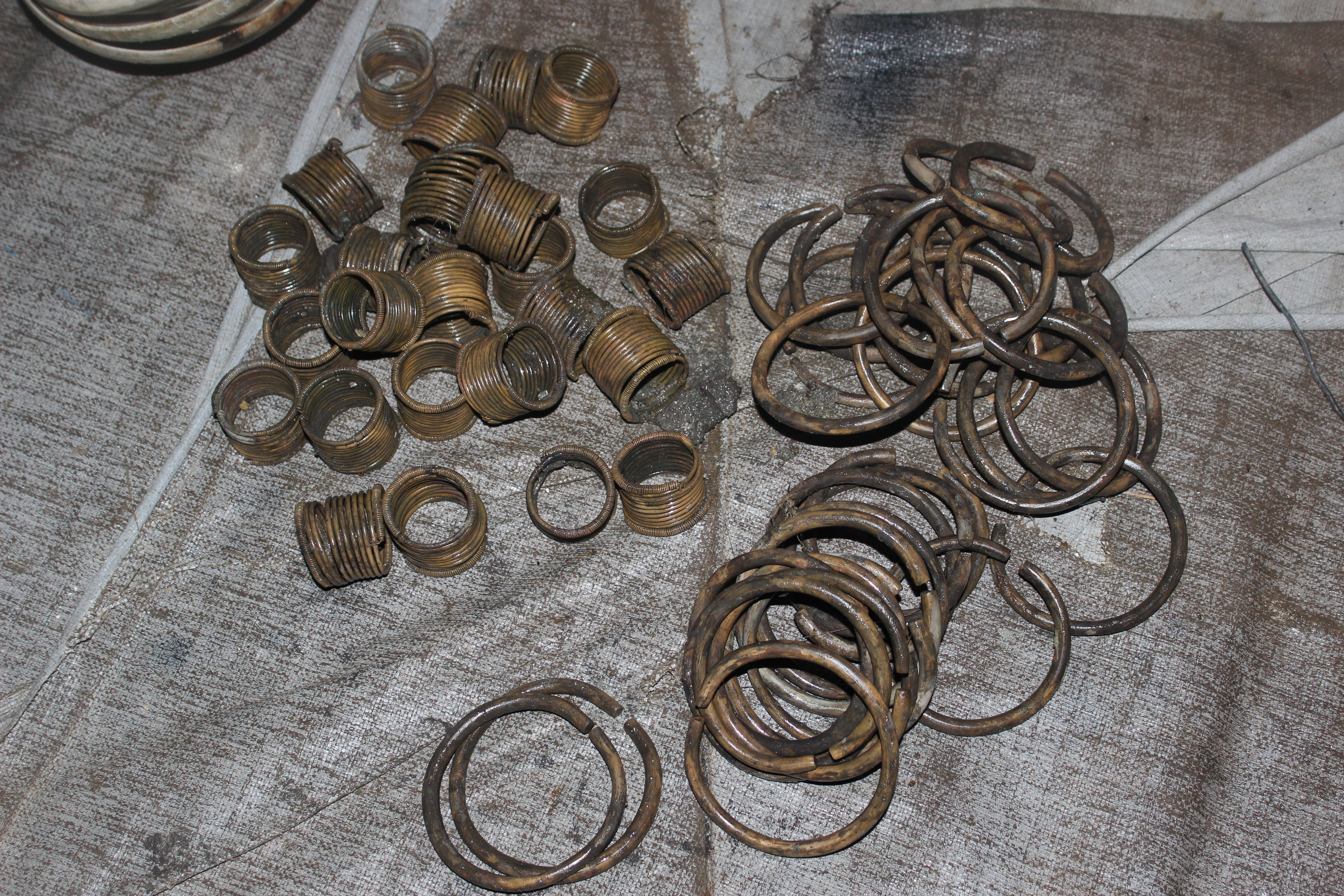 Piles of copper-alloy anklets and bracelets immediately after recovery.