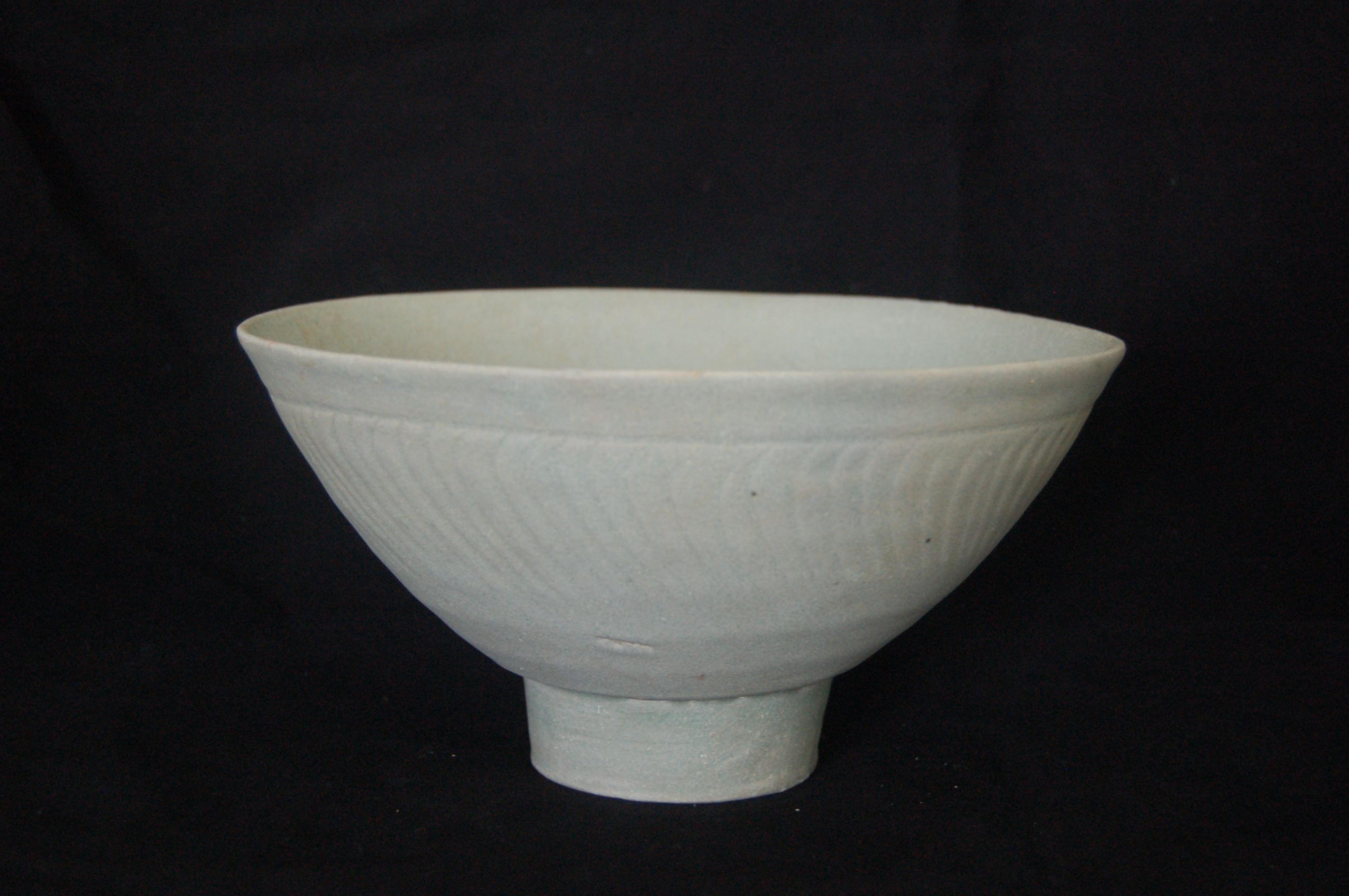 Medium bowl with a slightly everted rim, gently rounded wall with incised striations, lightly incised wavy or floral decorations on the interior, and a high carved foot-ring. Diameter 19.5 cm, height 10 cm.