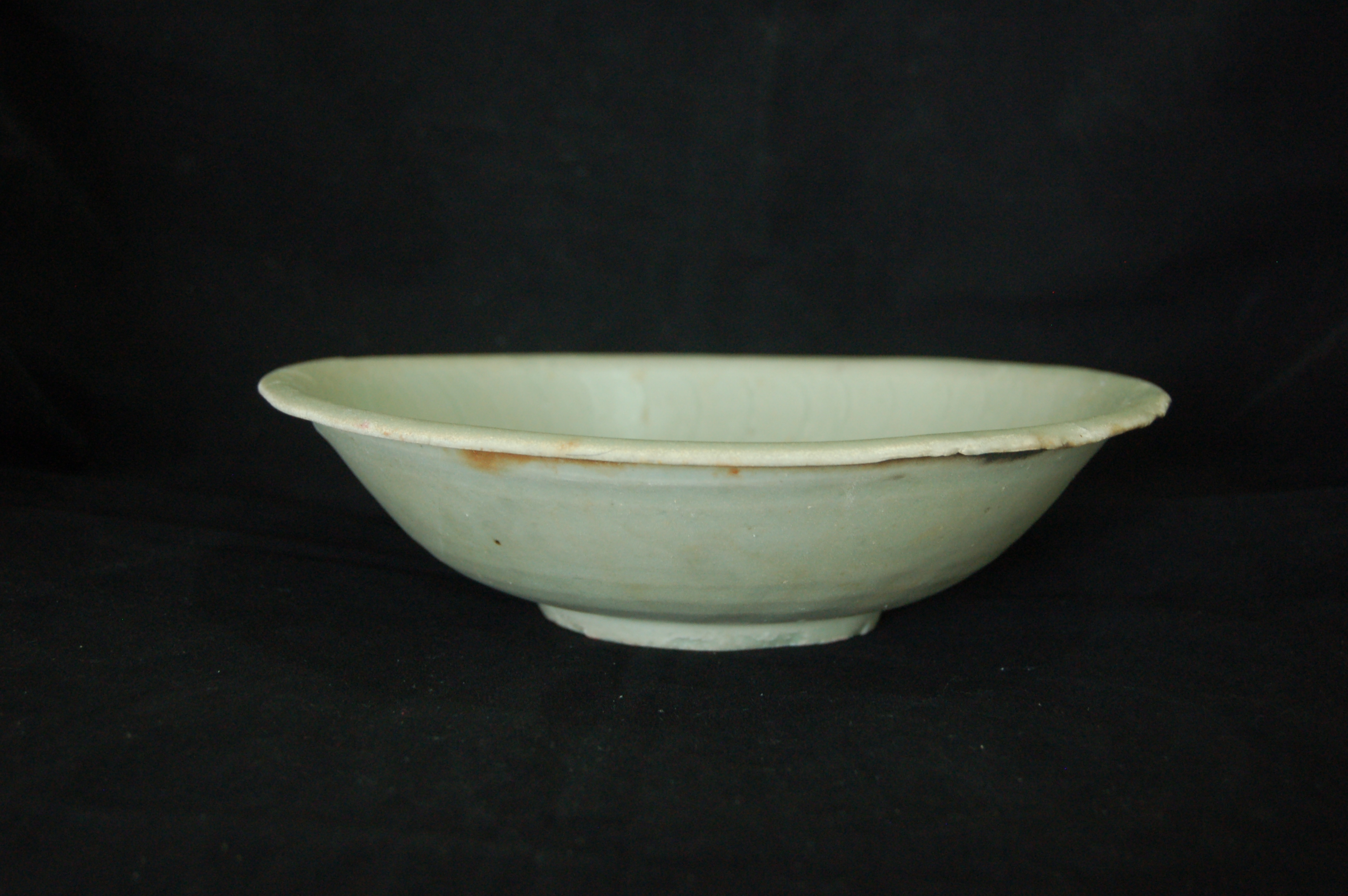 Green-glazed shallow bowl with an everted rim, rounded walls and a carved foot-ring. The well is decorated with incised waves and a central cloud while the cavetto displays paired striations. Diameter 22 cm, height 6 cm.