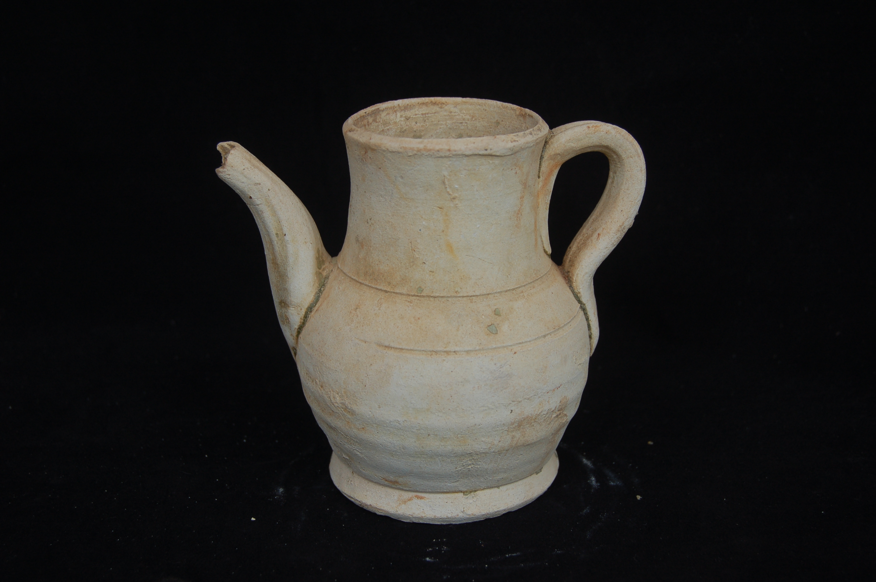 Small ewer with a wide straight neck, curved spout and strap handle. The foot is flared with a flat base. Diameter 9 cm, height 12 cm.