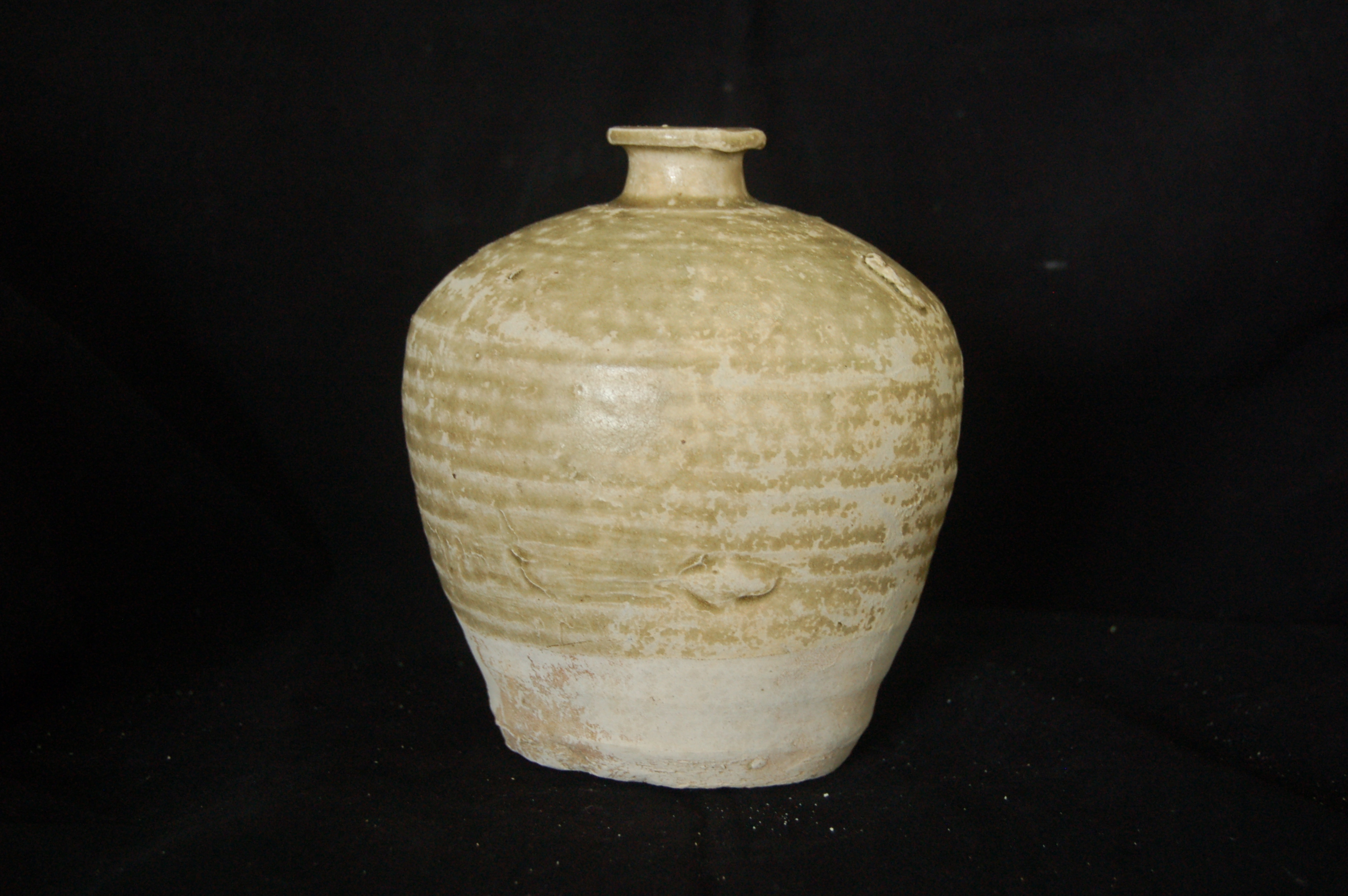 Small-mouth jar with olive green glaze stopping short of the flat base. Short neck with flared mouth-rim. Diameter 13.5 cm, height 15 cm.