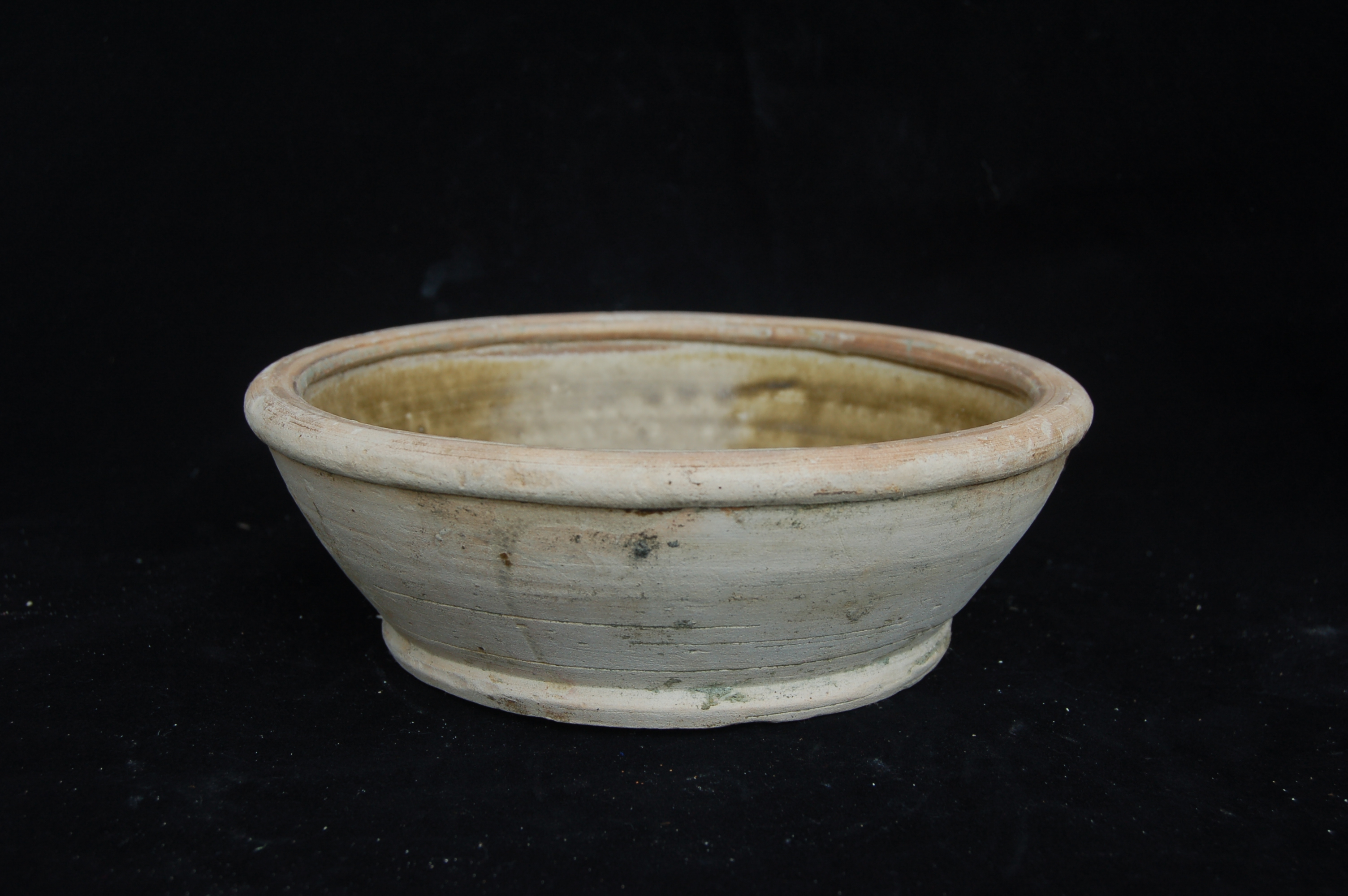 Small basin with olive-green glaze, decorated with a pair of flying birds. It has straight walls with a folded rim, and a flat base. Diameter 20 cm, height 6.5 cm.