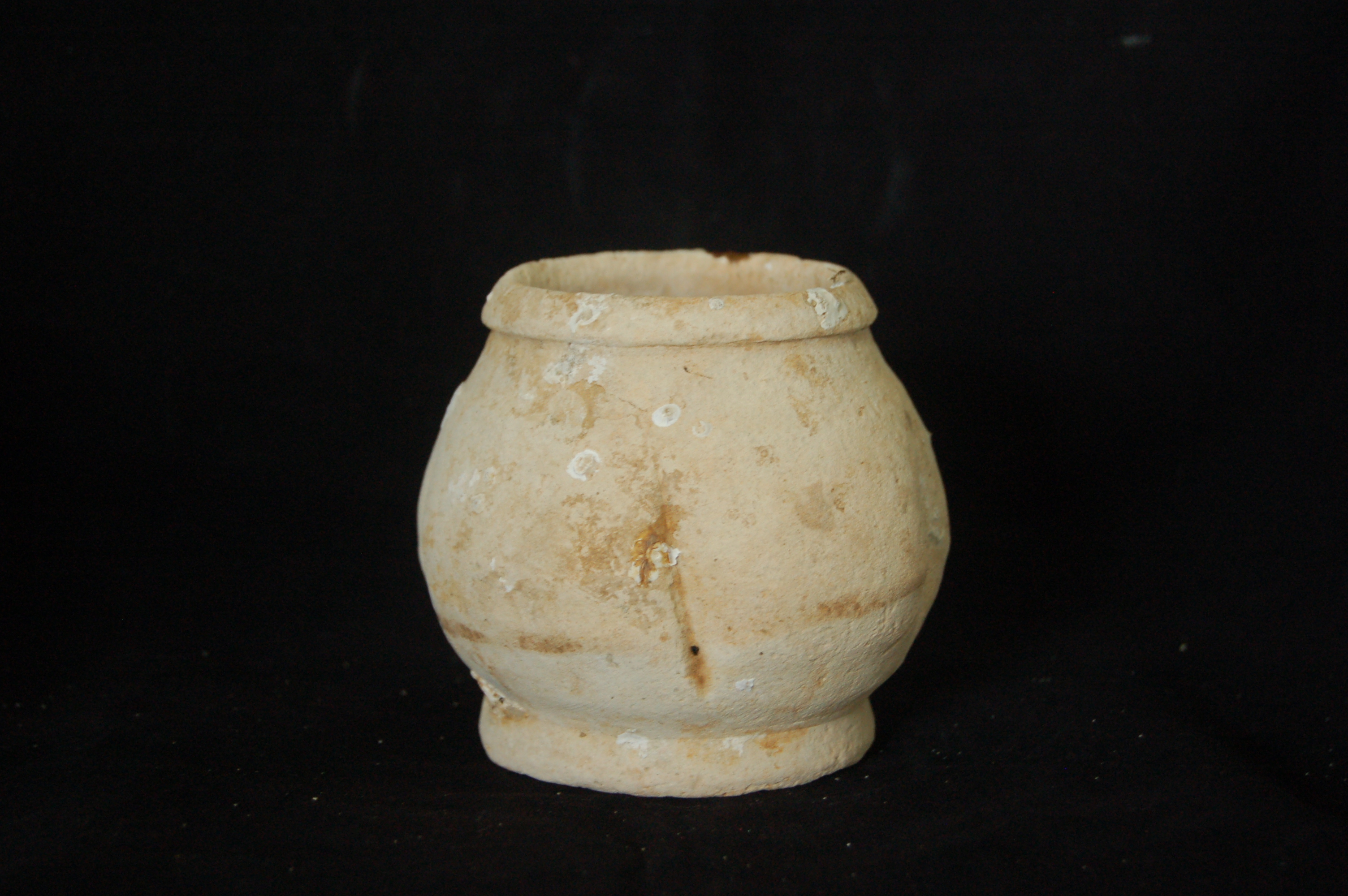 Small squat wide-mouth jar, four lobed, with a folded mouth-rim and a crudely carved foot-ring. Diameter 10 cm, height 9 cm.