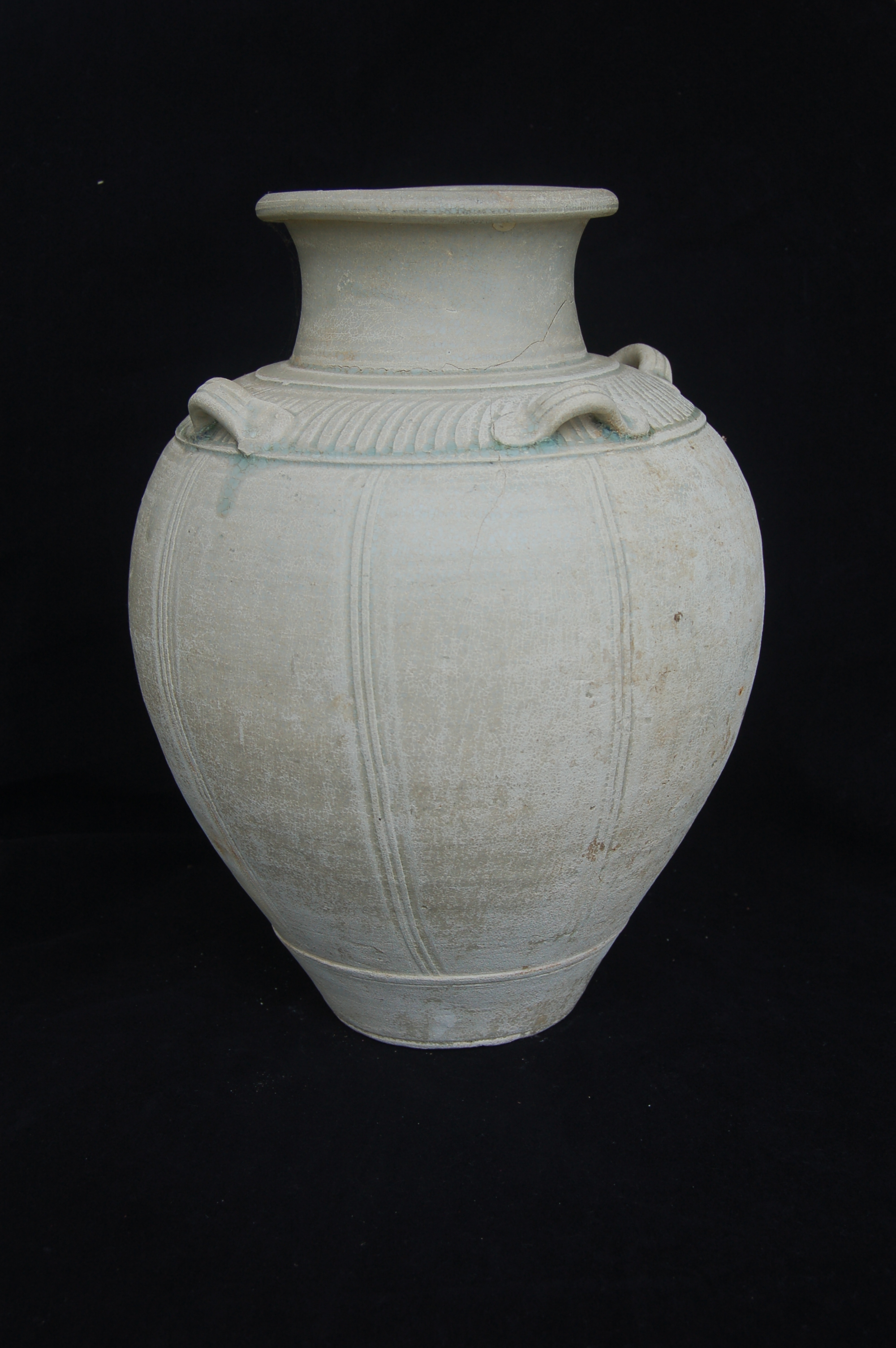 Decorated jar with remnants of <em>qingbai</em> glaze. Gently flared neck with a folded mouth-rim, four lug-handles on the shoulder, and a carved foot-ring. The body is divided into eight panels by duos of combed vertical lines, while the shoulder is circled by elegantly spiralled striations. Diameter 22 cm, height 30 cm.