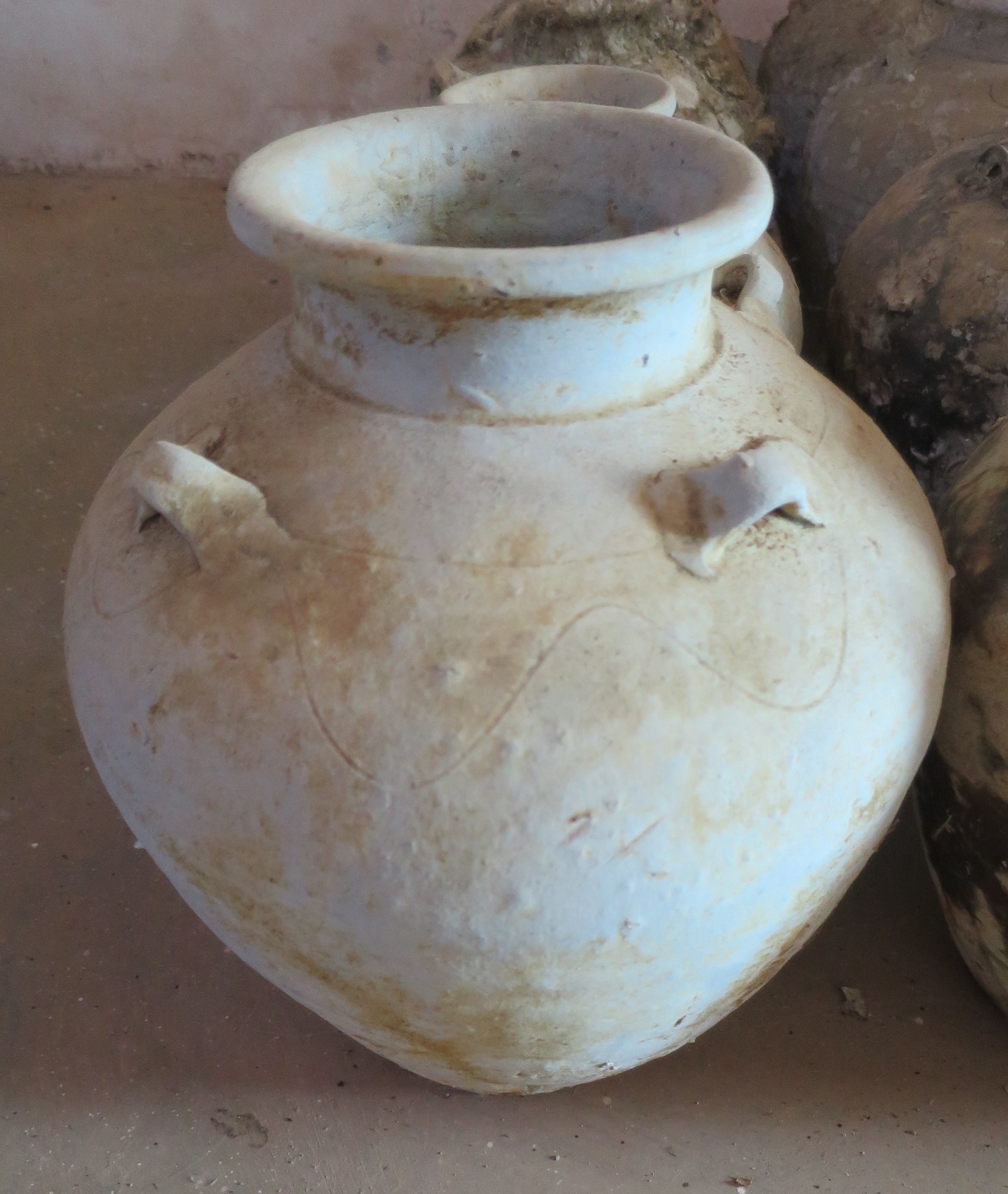 Jar with incised wavy decoration on the lower shoulder, four lug-handles, a short straight neck and a folded mouth-rim. Flat base. Diameter 20-31 cm, height 27-40 cm.